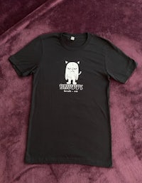 a black t - shirt with a white cat on it